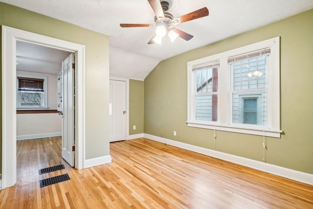 interior space with a textured ceiling, ceiling fan, lofted ceiling, and light wood-type flooring