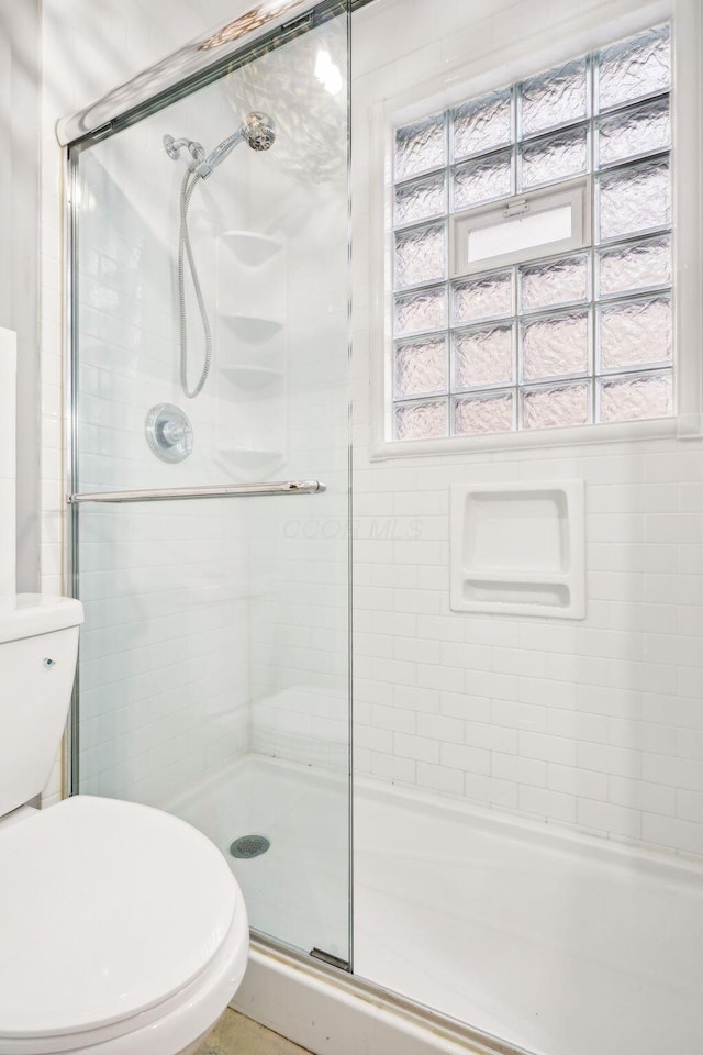 bathroom featuring toilet and a shower with shower door