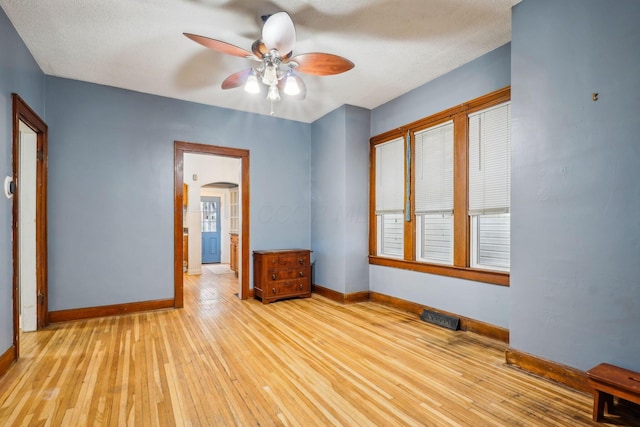 empty room featuring a textured ceiling, light hardwood / wood-style floors, and ceiling fan