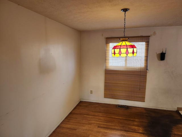 unfurnished dining area with wood-type flooring and a textured ceiling