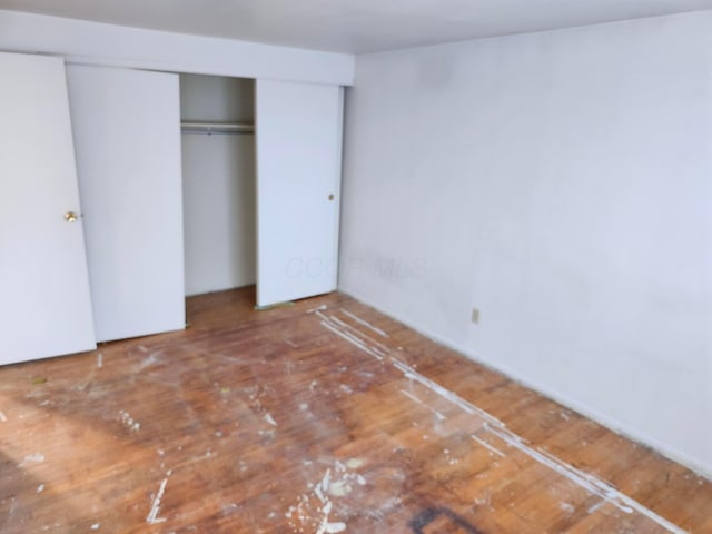 unfurnished bedroom featuring wood-type flooring and a closet