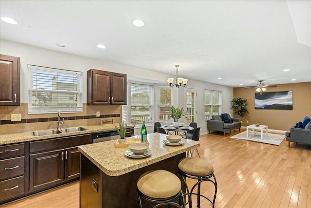 kitchen featuring sink, a center island, pendant lighting, a breakfast bar, and light wood-type flooring