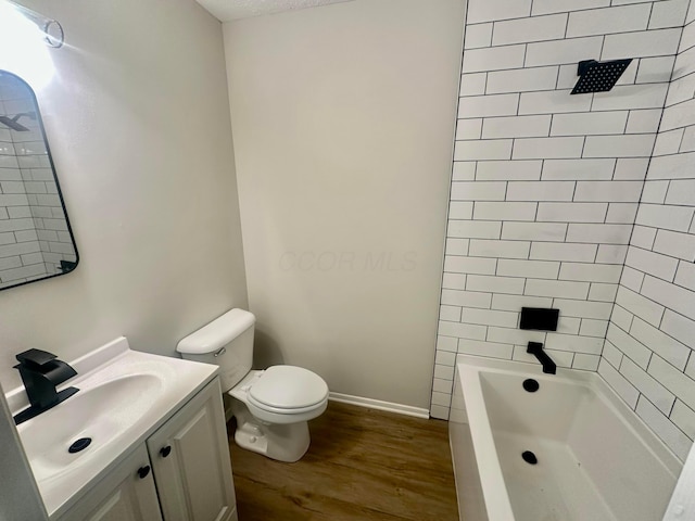 full bathroom featuring vanity, hardwood / wood-style floors, tiled shower / bath combo, and toilet