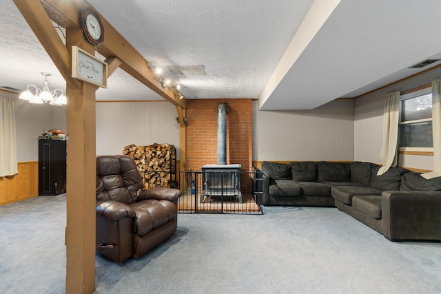 carpeted living room featuring a notable chandelier, a wood stove, a textured ceiling, and wooden walls