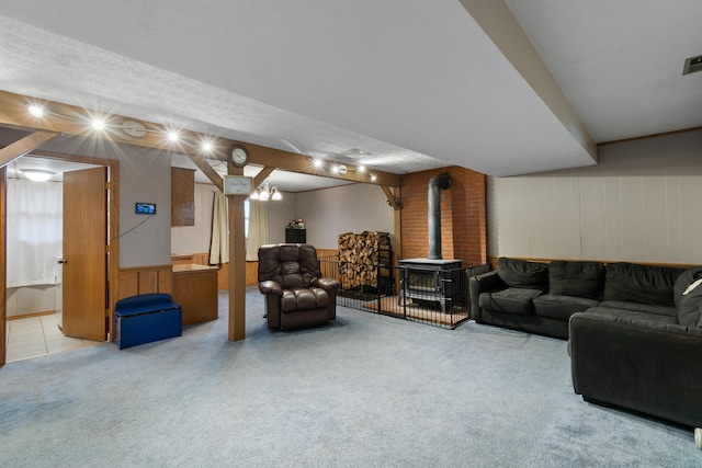 living room with light carpet, a textured ceiling, a wood stove, and wooden walls