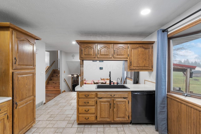 kitchen with a textured ceiling, black dishwasher, and sink