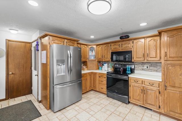 kitchen featuring black appliances, a textured ceiling, and tasteful backsplash