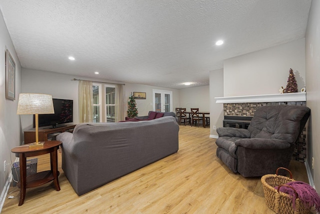 living room with a fireplace, light hardwood / wood-style floors, and a textured ceiling