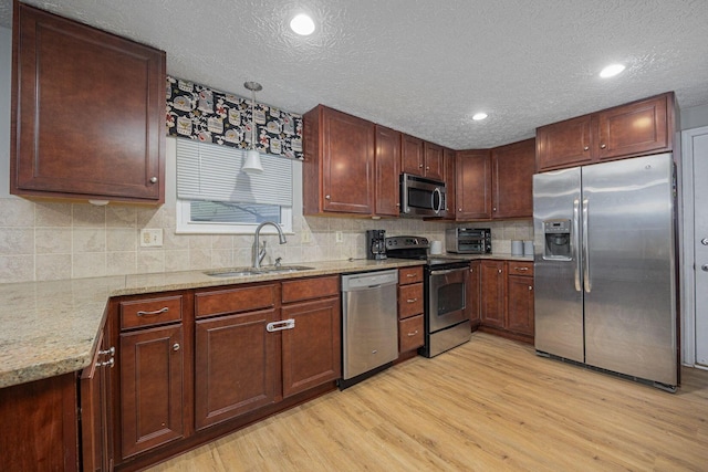 kitchen featuring light hardwood / wood-style floors, light stone counters, sink, and appliances with stainless steel finishes