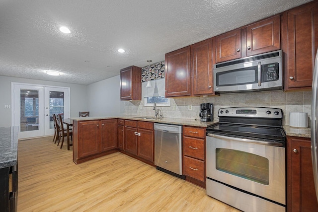 kitchen with backsplash, french doors, light wood-type flooring, a wealth of natural light, and stainless steel appliances