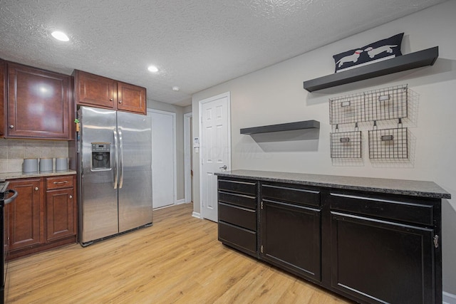 kitchen featuring stainless steel fridge, stove, light hardwood / wood-style floors, and a textured ceiling