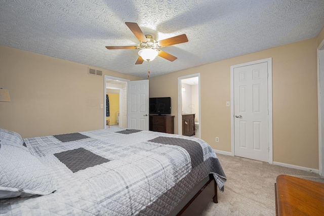 carpeted bedroom featuring ceiling fan, ensuite bathroom, and a textured ceiling