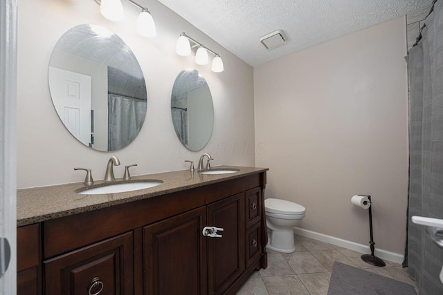 bathroom featuring tile patterned flooring, a textured ceiling, vanity, and toilet