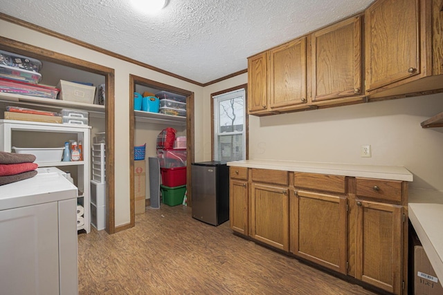 kitchen with stainless steel fridge, light wood-type flooring, a textured ceiling, crown molding, and washer / dryer