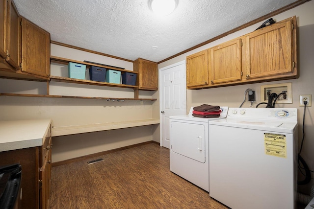 laundry room with cabinets, dark hardwood / wood-style flooring, ornamental molding, a textured ceiling, and washing machine and clothes dryer