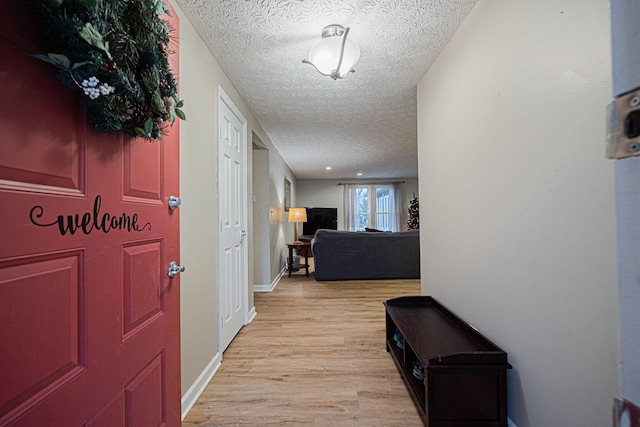 hallway featuring light wood-type flooring and a textured ceiling