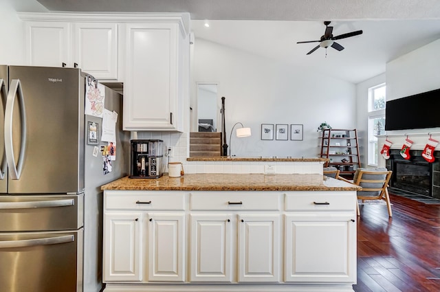 kitchen featuring backsplash, stainless steel fridge, white cabinets, and light stone countertops