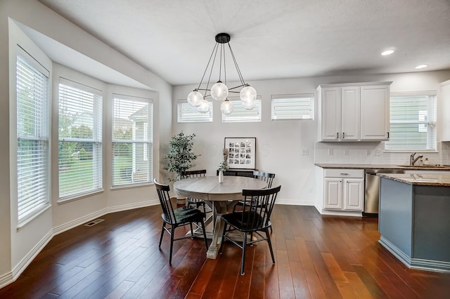 dining room with dark hardwood / wood-style flooring, sink, and a chandelier