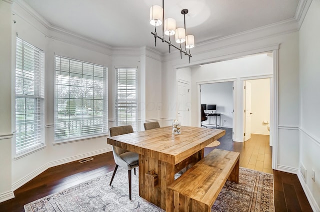 dining room featuring a chandelier, plenty of natural light, dark wood-type flooring, and ornamental molding