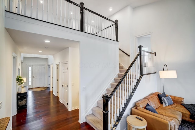 stairs with wood-type flooring and a towering ceiling