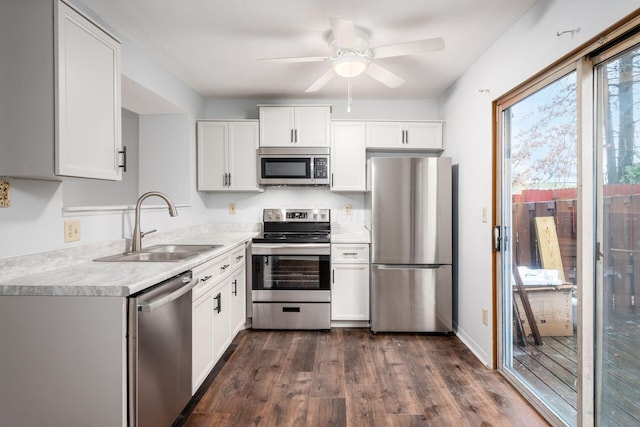 kitchen with ceiling fan, sink, stainless steel appliances, dark hardwood / wood-style flooring, and white cabinets