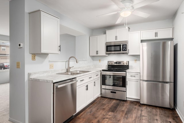 kitchen with appliances with stainless steel finishes, ceiling fan, dark wood-type flooring, sink, and white cabinets