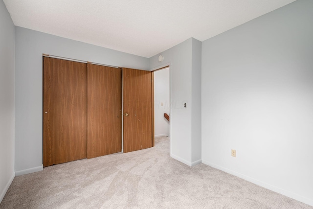 unfurnished bedroom featuring light colored carpet and a closet