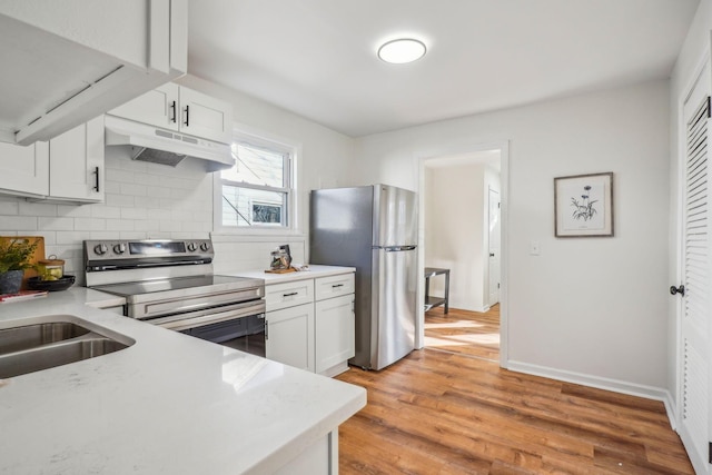 kitchen featuring sink, tasteful backsplash, light hardwood / wood-style floors, white cabinets, and appliances with stainless steel finishes