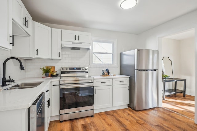 kitchen with sink, light wood-type flooring, tasteful backsplash, white cabinetry, and stainless steel appliances