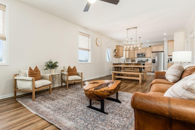 living room featuring hardwood / wood-style flooring, ceiling fan with notable chandelier, and sink