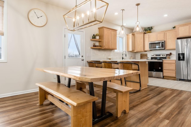 kitchen featuring light brown cabinetry, stainless steel appliances, and pendant lighting