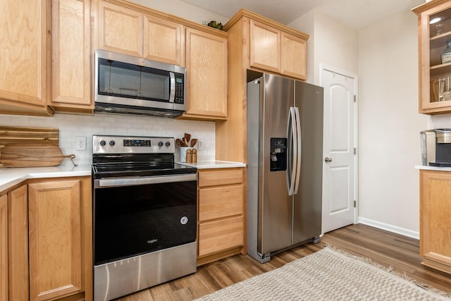 kitchen featuring appliances with stainless steel finishes, light brown cabinets, tasteful backsplash, and wood-type flooring