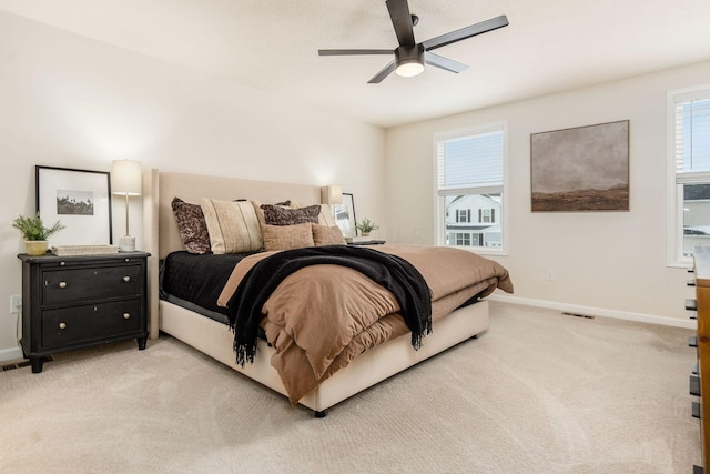 bedroom with multiple windows, light carpet, and ceiling fan