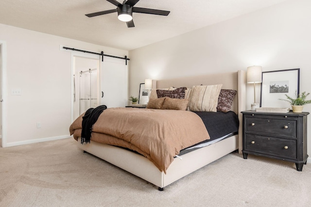 carpeted bedroom featuring a barn door and ceiling fan