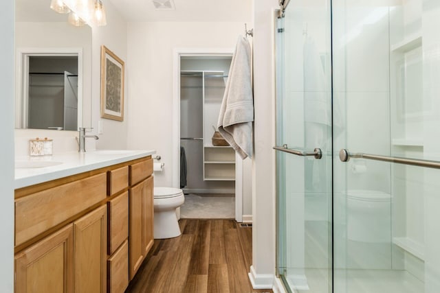 bathroom with vanity, hardwood / wood-style flooring, toilet, and a shower with door