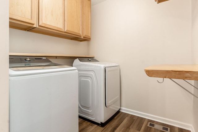 laundry area featuring dark wood-type flooring, washer and clothes dryer, and cabinets