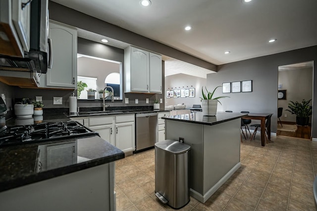 kitchen featuring a center island, dark stone counters, white cabinets, sink, and appliances with stainless steel finishes