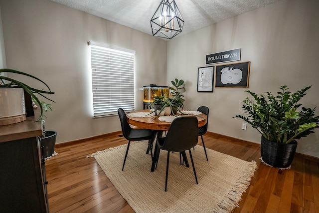 dining room with hardwood / wood-style floors, a textured ceiling, and a notable chandelier