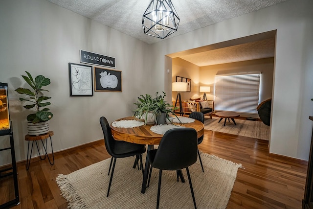 dining room featuring an inviting chandelier, a textured ceiling, and hardwood / wood-style flooring