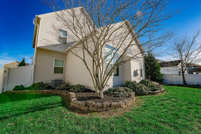 view of side of property with a lawn and central AC