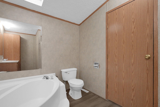 bathroom featuring hardwood / wood-style floors, lofted ceiling, crown molding, toilet, and a textured ceiling