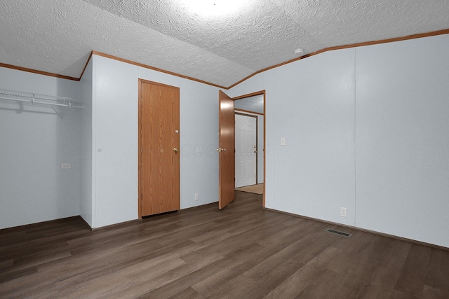 unfurnished bedroom with dark hardwood / wood-style floors, crown molding, a textured ceiling, lofted ceiling, and a closet