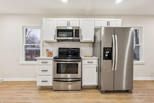 kitchen featuring white cabinets, light wood-type flooring, stainless steel appliances, and a wealth of natural light