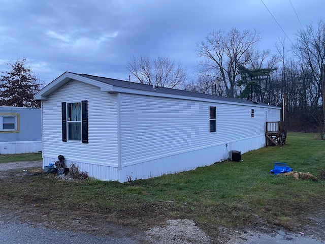 view of side of property featuring central AC and a lawn