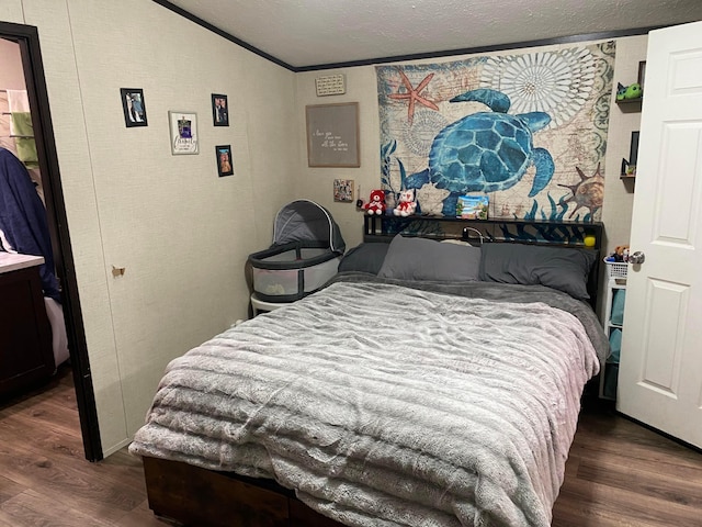 bedroom featuring a textured ceiling, ornamental molding, and dark wood-type flooring