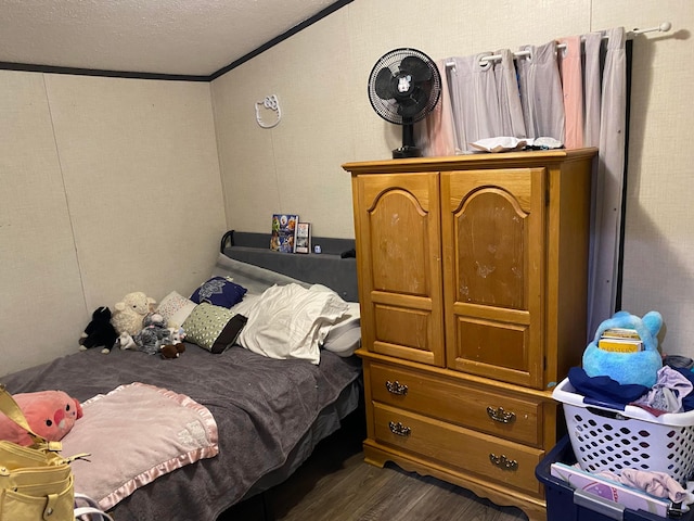 bedroom with dark wood-type flooring, a textured ceiling, and ornamental molding