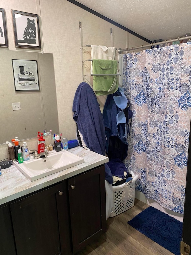 bathroom with a shower with curtain, hardwood / wood-style floors, a textured ceiling, vanity, and ornamental molding