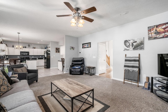 carpeted living room featuring ceiling fan with notable chandelier and a textured ceiling