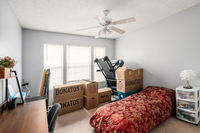 carpeted bedroom with ceiling fan and a textured ceiling