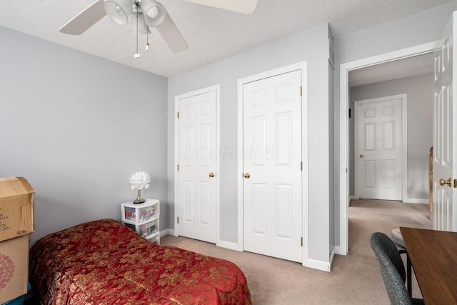 bedroom with a textured ceiling, light colored carpet, and ceiling fan